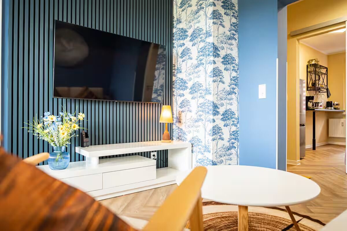 Wohnzimmer mit blauer Wandgestaltung, Lamellenpaneelen und Mustertapete