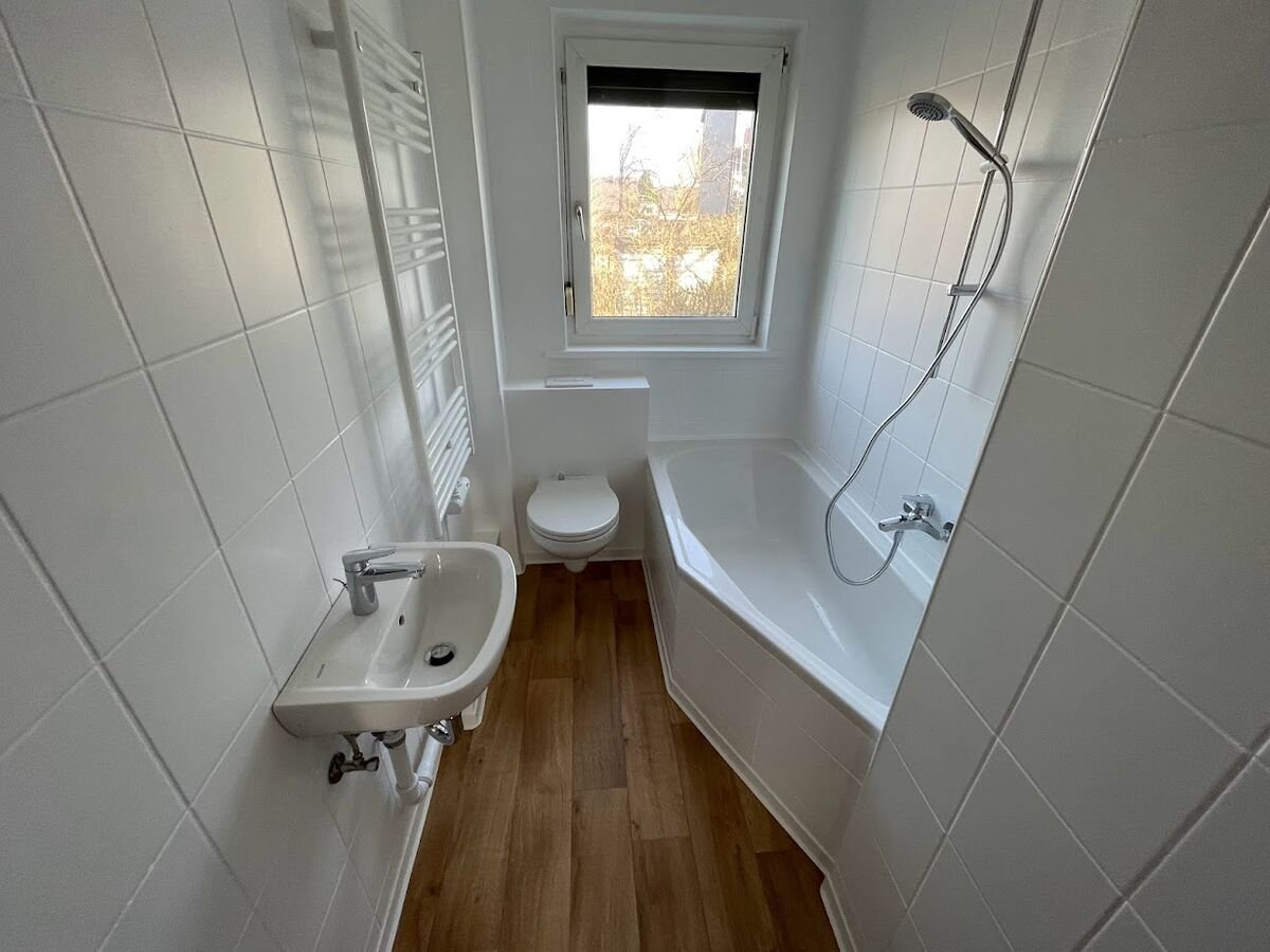 Modernisiertes weißes Badezimmer mit Eckbadewanne und Vinylboden in Holzoptik, Schönebeck
