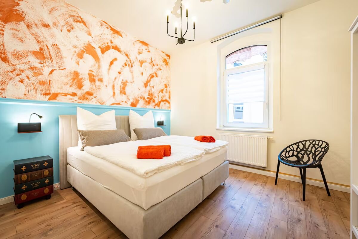 Schlafzimmer in Himmelblau mit grafischen Wandpaneelen und Palmenleuchte, kreative Raumgestaltung Magdeburg