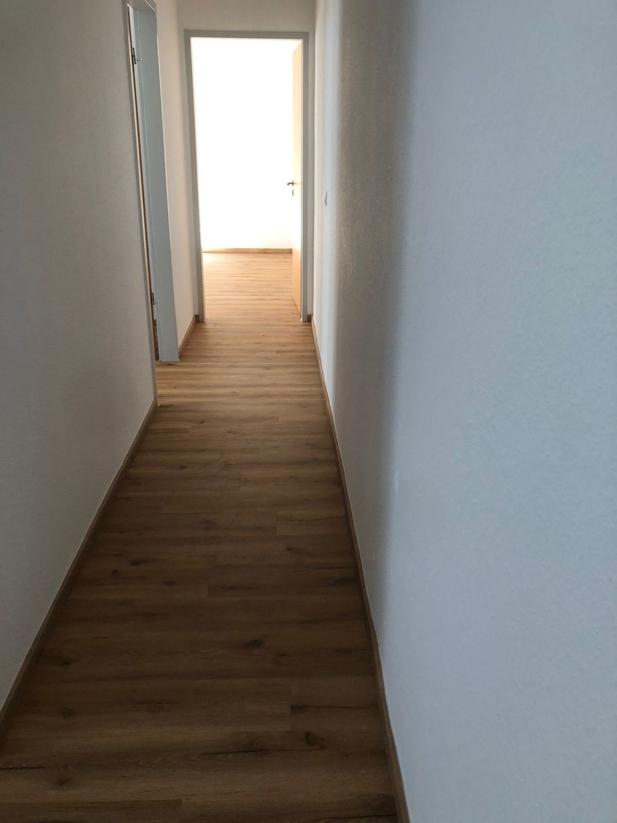 Langer Flur mit neuem Bodenbelag in Eichenoptik – Wohnungsrenovierung Magdeburg
